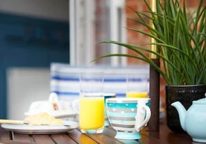 A breakfast setting with a plate of food, a glass of orange juice, and a striped mug on a wooden table. - The Nets - Fantastic 3 bedroom house with parking (Filey)