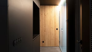 Un pasillo con una puerta de madera, un accesorio de iluminación y una lámpara en la pared.