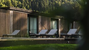 Un edificio moderno con piscina y sillones de descanso.
