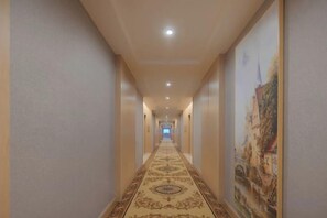 A hotel corridor with a patterned carpet, walls with artwork, and recessed lighting. - Changtai Jinbang International Hotel (Zhangzhou)