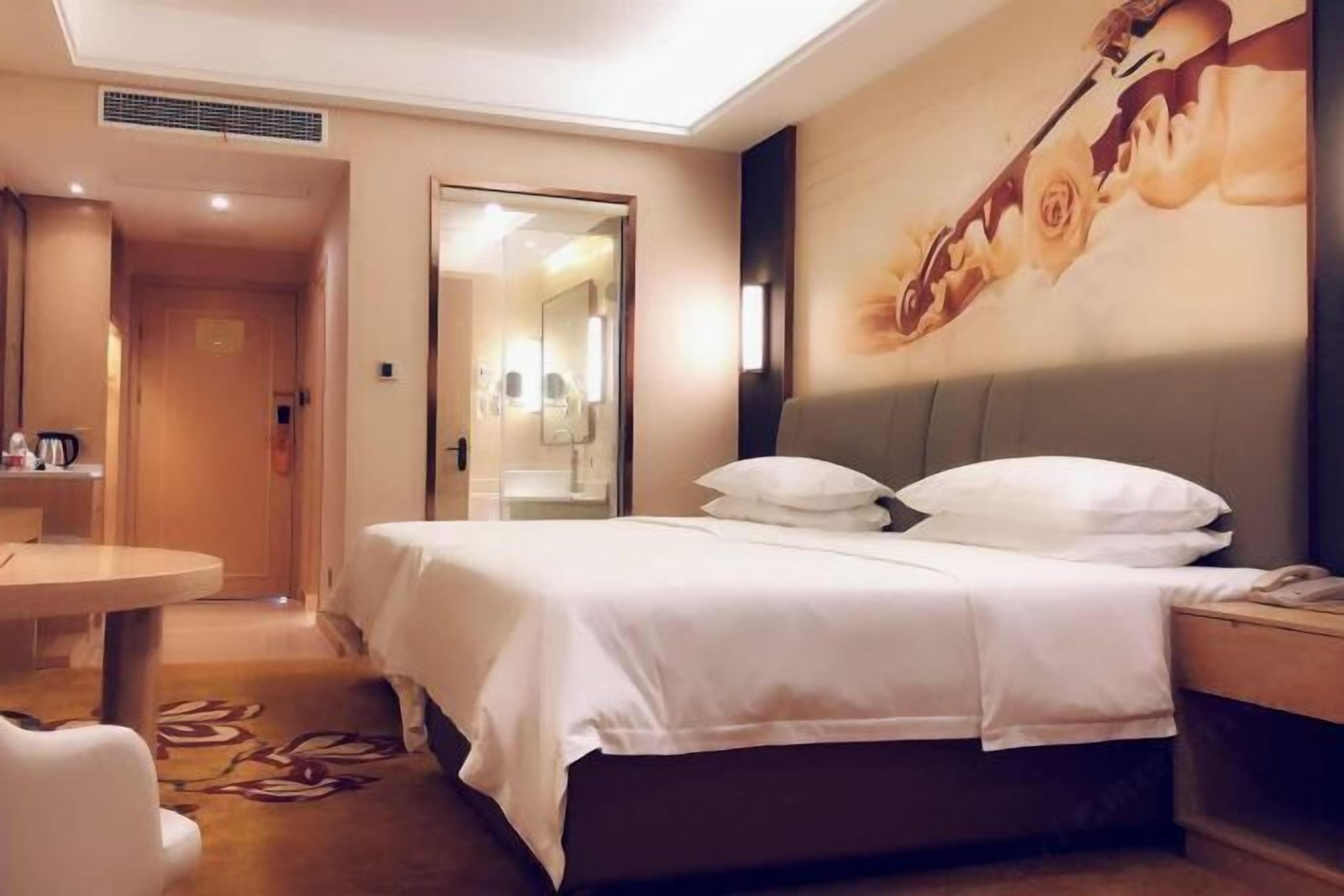 A hotel room with a bed, bedside table, and a small round table.