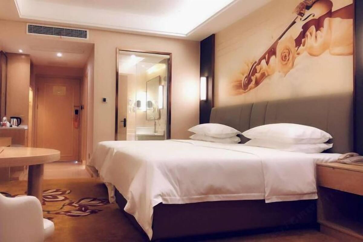 A hotel room with a bed, bedside table, and a small round table.