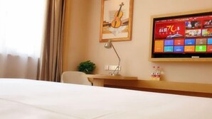 A hotel room with a bed, a desk, a TV, a lamp, and a framed picture on the wall. - Changtai Jinbang International Hotel (Zhangzhou)