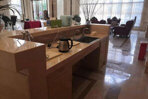 Eine Küche mit Spüle, Arbeitsfl äche und Wasserkocher. Im Hintergrund ist ein Essbereich mit Stühlen und einem Tisch zu sehen.