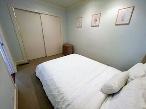 Ein Schlafzimmer mit einem Bett, einem Kleiderschrank und drei gerahmten Bildern an der Wand.