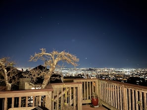 Nachtansicht von einem Balkon mit Blick auf eine Stadtlandschaft, einem Holgitter und einem Blumentopf.