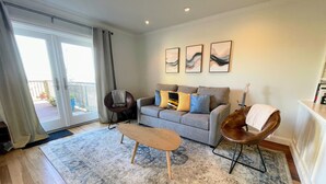 Un salon moderne avec un canapé gris, une table basse en bois et un tapis à motifs.