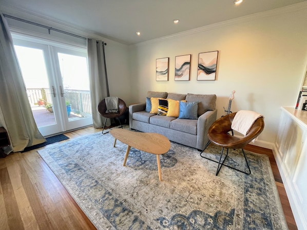 Ein modernes Wohnzimmer mit einem grauen Sofa, einem Holztisch und einem gemusterten Teppich.