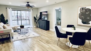 A modern living room with a sofa, coffee table, and dining area with chairs. - Oasis Resort Style Condo 2/2 (Naples)
