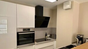 Une cuisine moderne équipée d’appareils électroménagers en acier inoxydable, d’un four encastré, d’un four à micro-ondes et d’une machine à café.