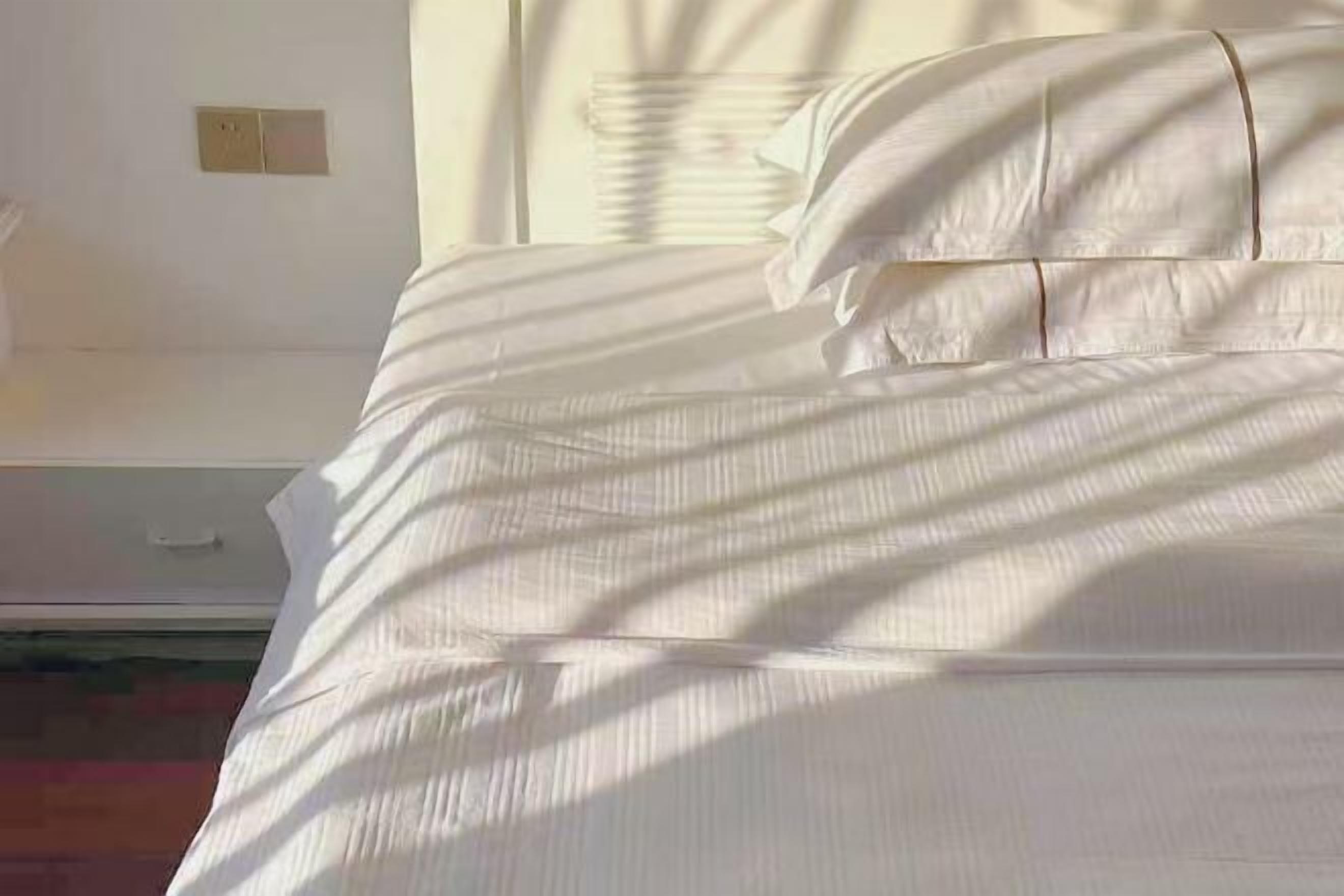 A bed with white linens and a headboard.