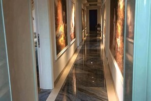 A hallway with marble flooring, framed artwork on the walls, and a door at the end. - Lvsenlingongyu (Chenzhou)