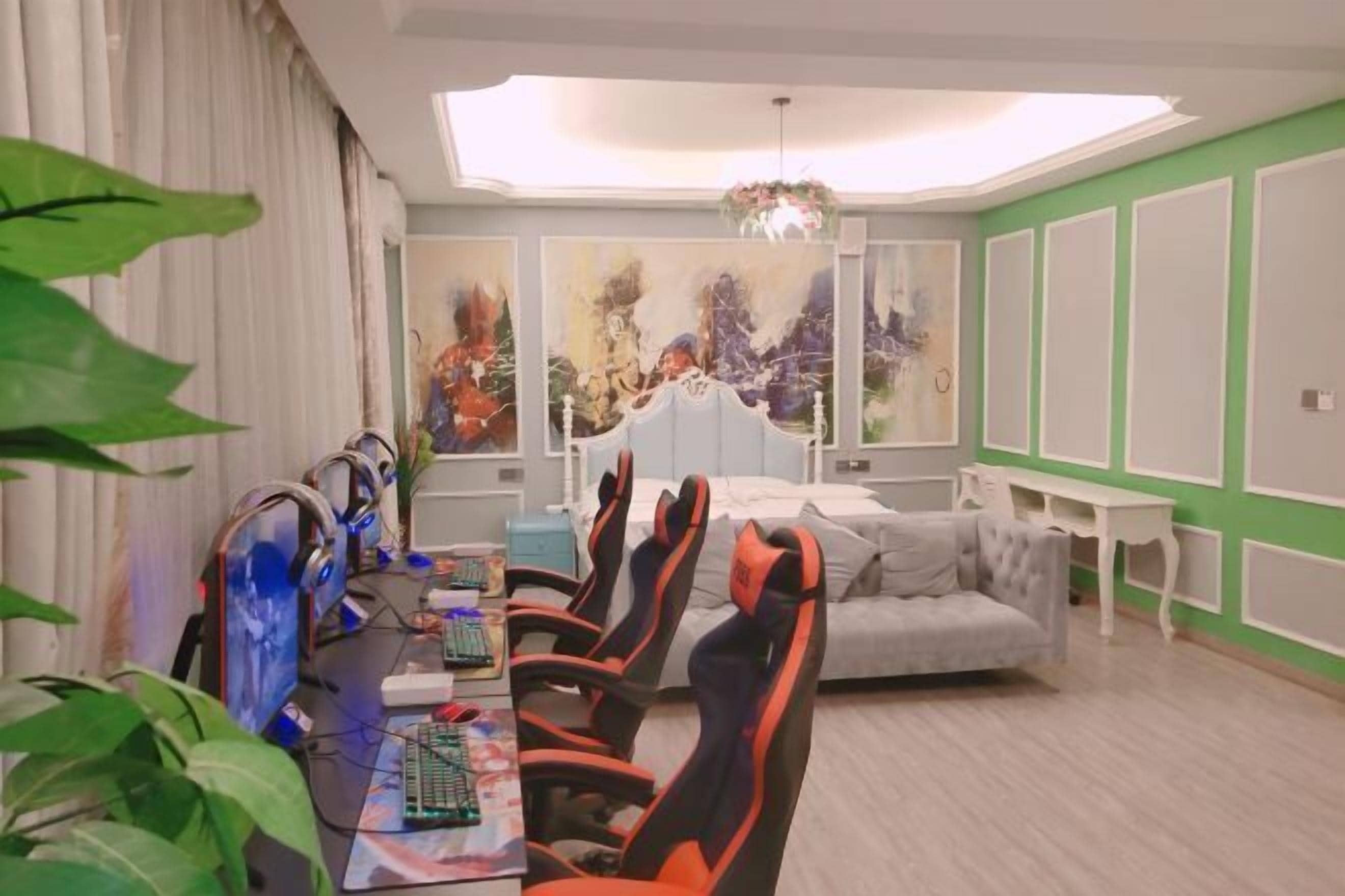 A modern room with a gaming setup, a grey sofa, and a large abstract painting on the wall.