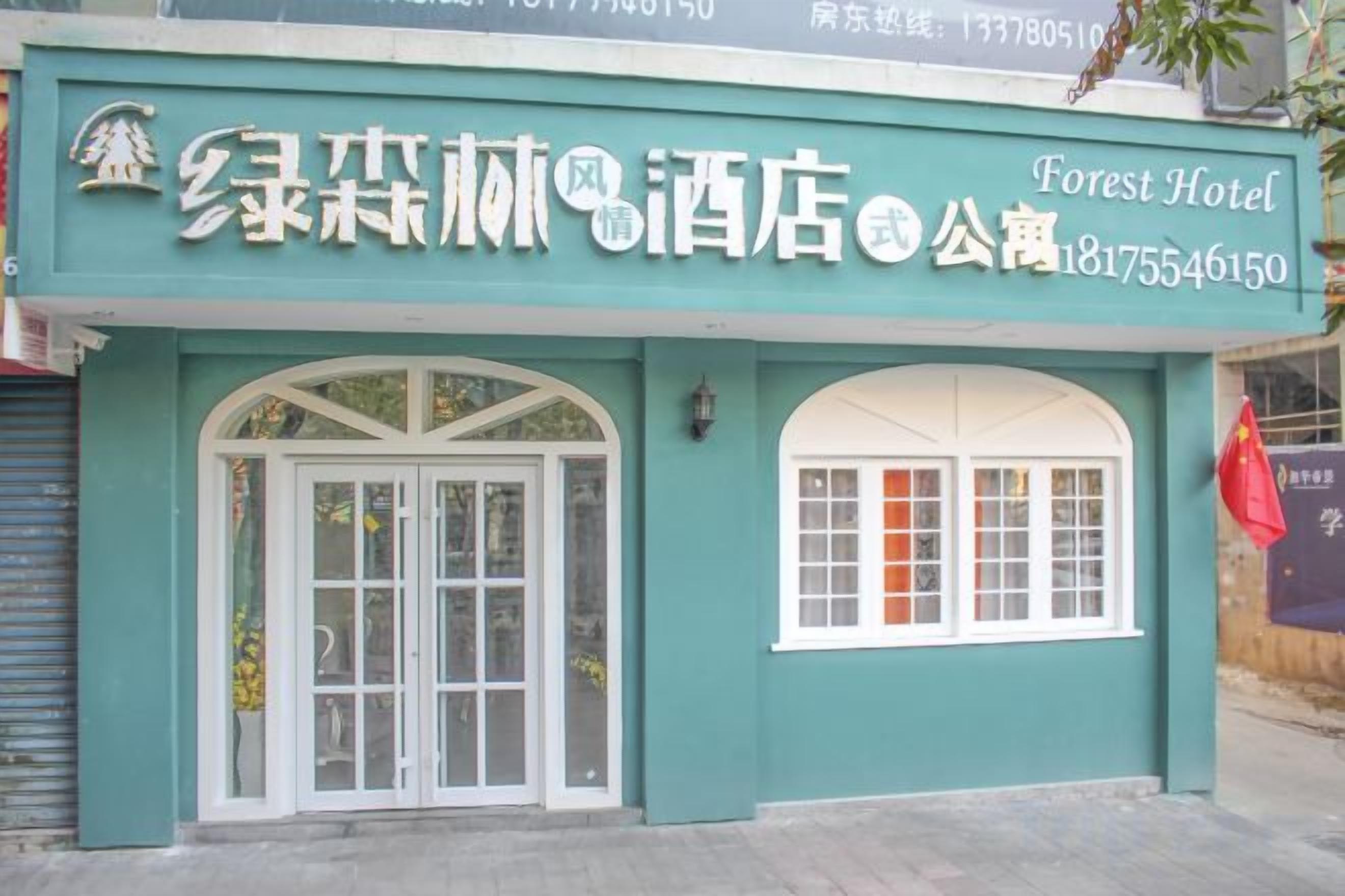 Entrada de hotel com placa indicando Forest Hotel, apresentando uma grande porta em arco e uma janela menor à direita.