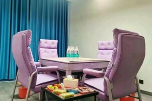 A conference room with a table and four purple chairs, a tray with snacks, and water bottles on the table.
