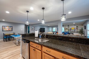 A modern kitchen with granite countertops, a built-in sink, and pendant lighting.
