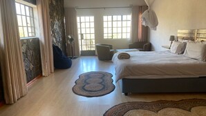 A bedroom with a bed, two windows, a fan, and a chair.