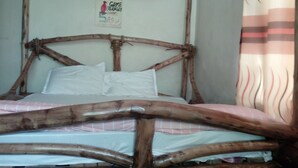 A bed with a wooden frame and a pink bedspread. - natural environment from river side (ARUSHA)