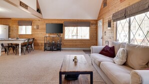 Un intérieur de chalet chaleureux comprenant un coin repas, un canapé, une table basse et un téléviseur.