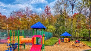 Une aire de jeux avec un toboggan, des structures d’escalade et une balançoire.
