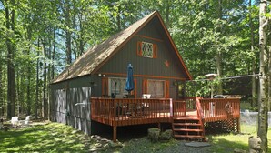 Une cabane avec une terrasse, un porche et une pancarte de bienvenue.
