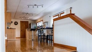 A wooden staircase leading to a dining area with a kitchen in the background. - Waterfront Cottage with HotTub! Next to OFSC trails (French River)