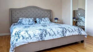 A bedroom with a bed, a nightstand, and a mirror. - Waterfront Cottage with HotTub! Next to OFSC trails (French River)