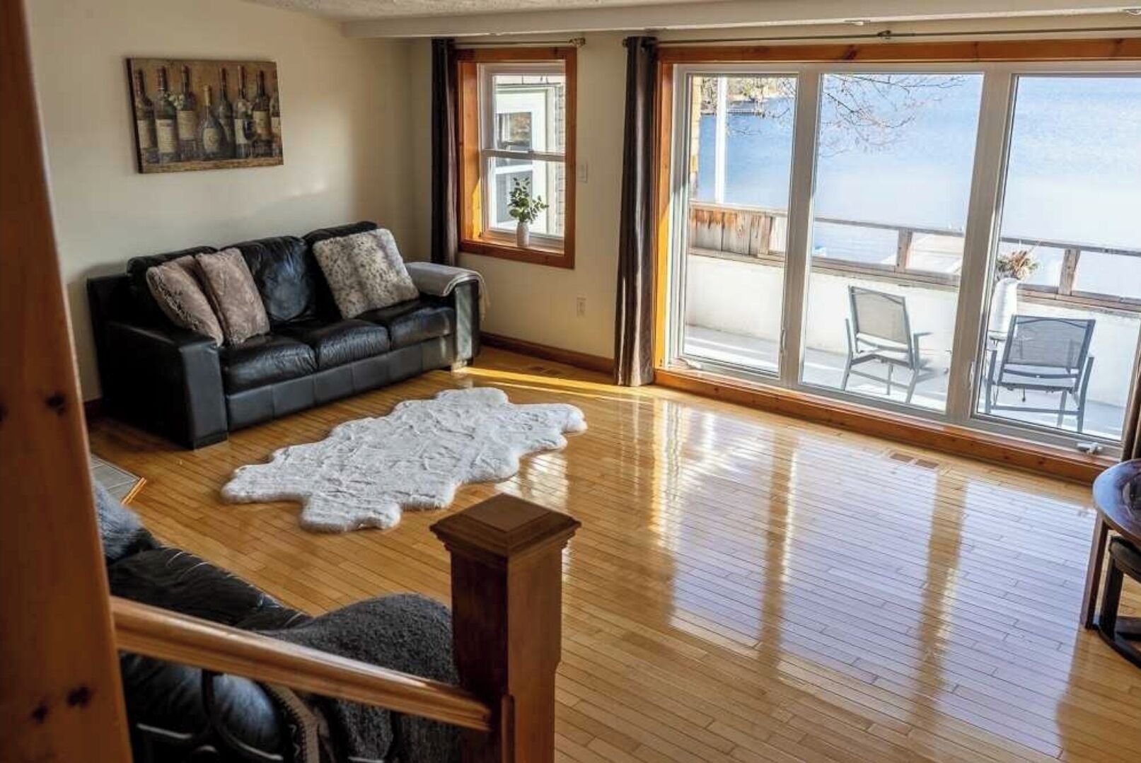 A living room with a leather sofa, a fur rug, and large windows overlooking a deck.