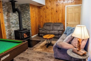 Relax in this inviting living room with a stove, comfortable sofa, and pool table.