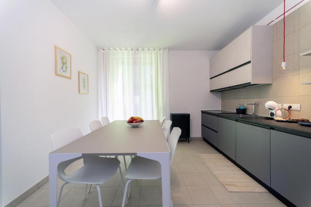 Een moderne keuken met een eettafel, stoelen en een schaal fruit.