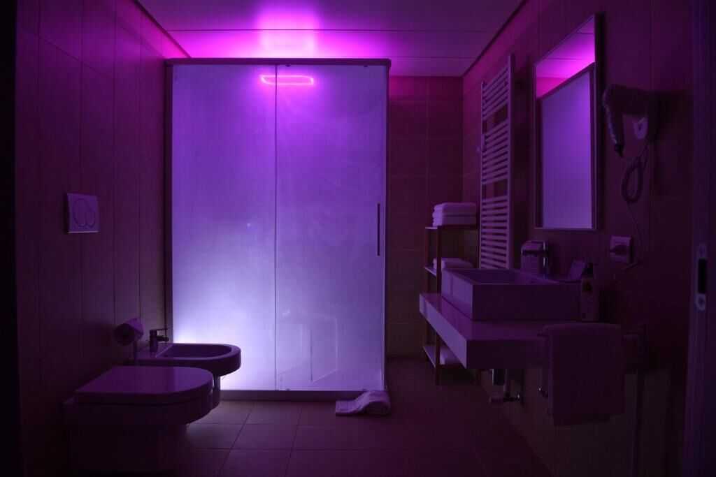 A modern bathroom with a large mirror, a sink, and a toilet.