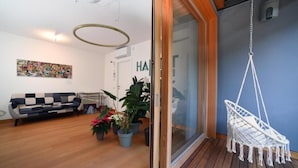 A modern living room with a sofa, potted plants, and a macrame hanging chair. - Habitat Apartments (Trento)