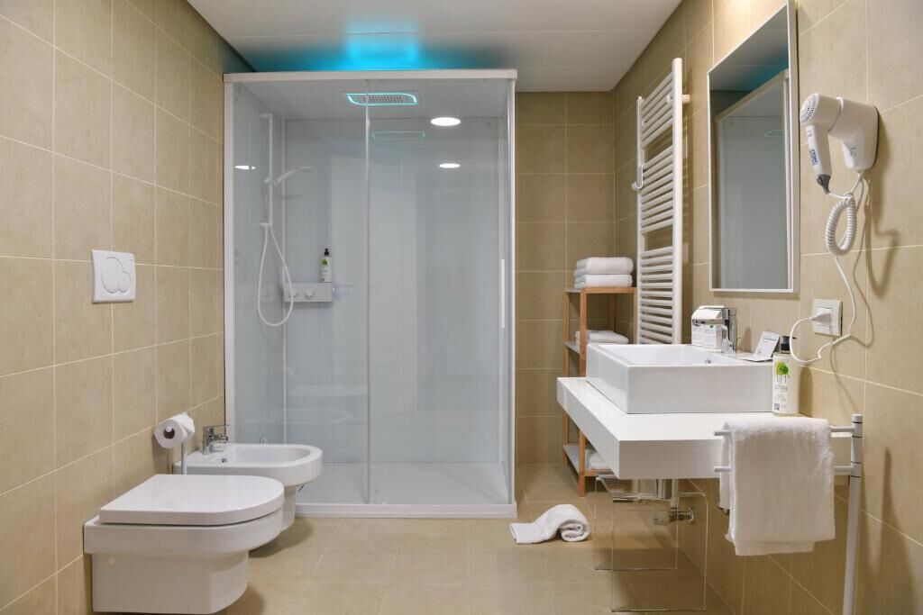 Une salle de bain moderne avec une douche à parois de verre, des toilettes, un lavabo et un porte-serviettes.