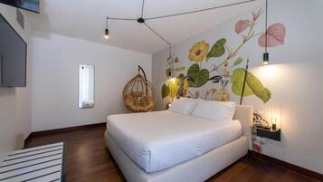 Un dormitorio moderno con una cama grande, una silla colgante, un televisor montado en la pared y un mural de flores.