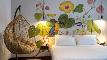 A bedroom with a hanging chair, a bed with white bedding, and a mural of flowers and a bird.
