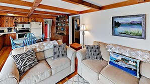 A cozy living room with a sofa set, a dining table with chairs, a kitchen area with wooden cabinets, and a painting on the wall. - Nest On Mount Desert Isle w Beach - 8 Mi to Acadia (Mt Desert)