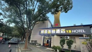 A hotel building with a prominent sign in a foreign language, a tall tower-like structure, and potted plants along the sidewalk. - 100 Inn (Wuhan Optics Valley Geoscience University) (Wuhan)