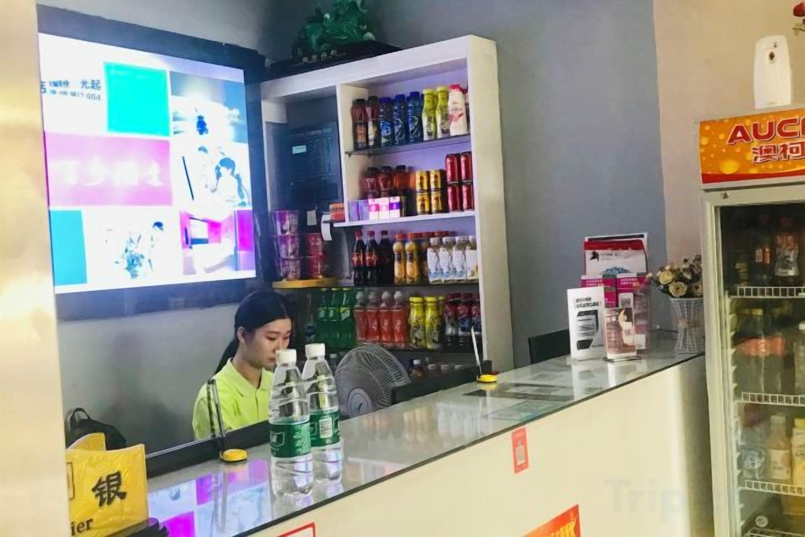 A reception area with a counter, a refrigerator, and shelves stocked with beverages.