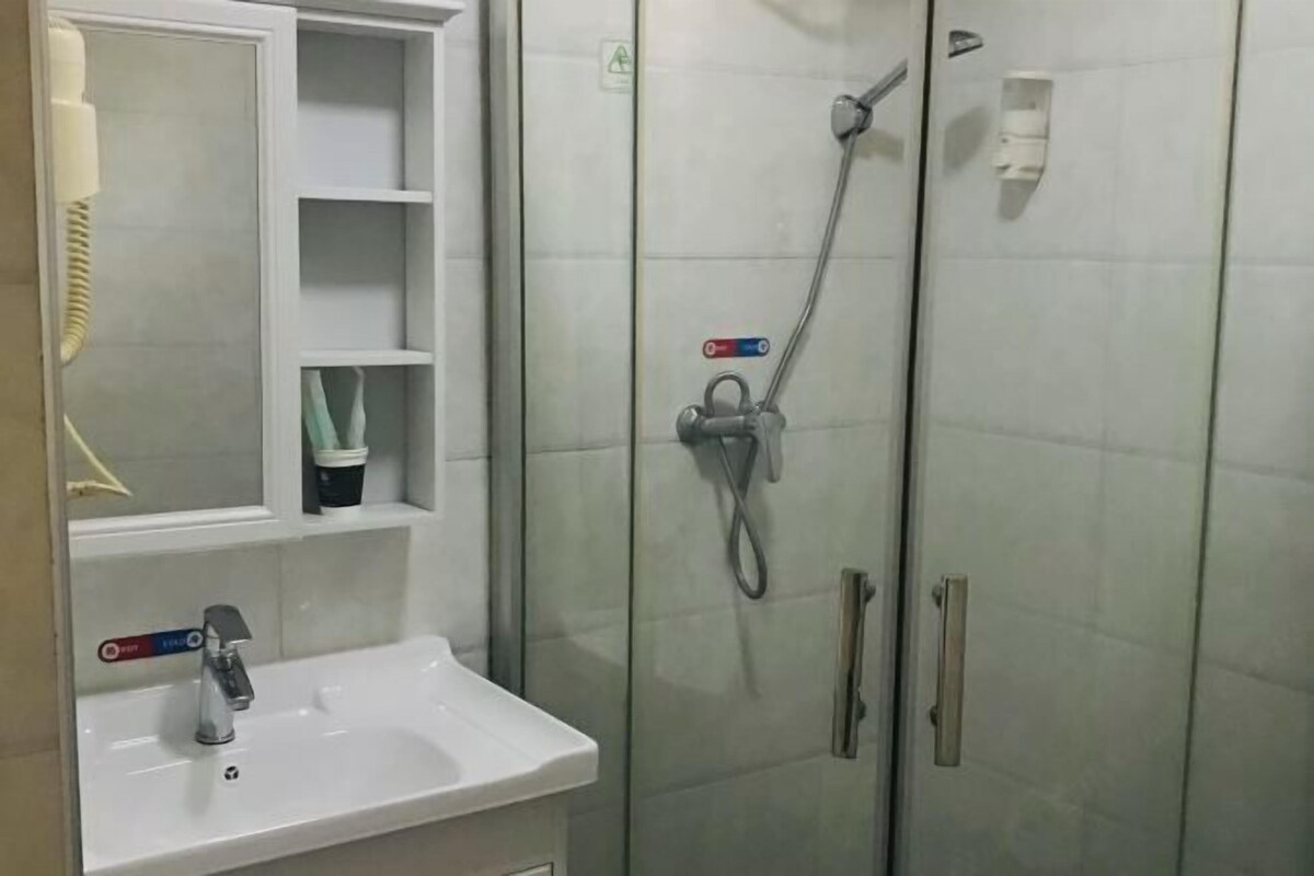 A bathroom with a white sink, a mirror, and a glass shower enclosure.
