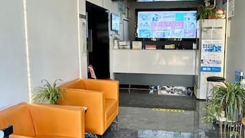 A reception area with a reception desk, a television screen, and seating.