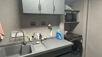 Een keuken met een spoelbak, een magnetron en een wasmachine.