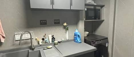 Una cocina con un lavabo, un microondas y una lavadora.