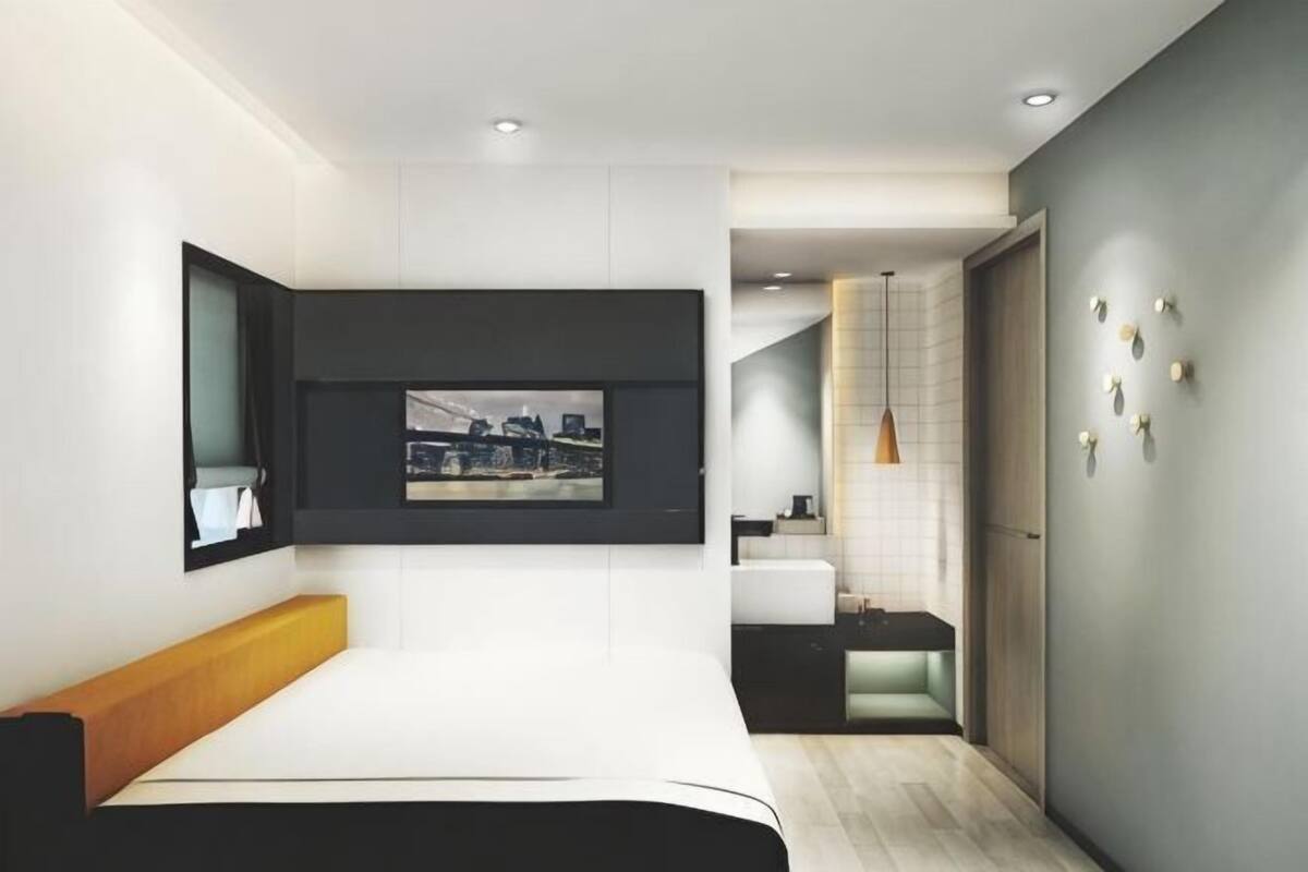 A modern bedroom with a bed, a mounted TV, and a cityscape view.