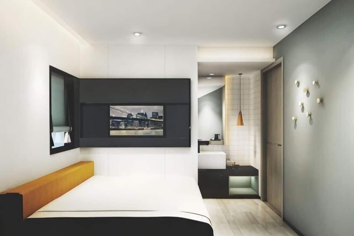 A modern bedroom with a bed, a mounted TV, and a cityscape view.