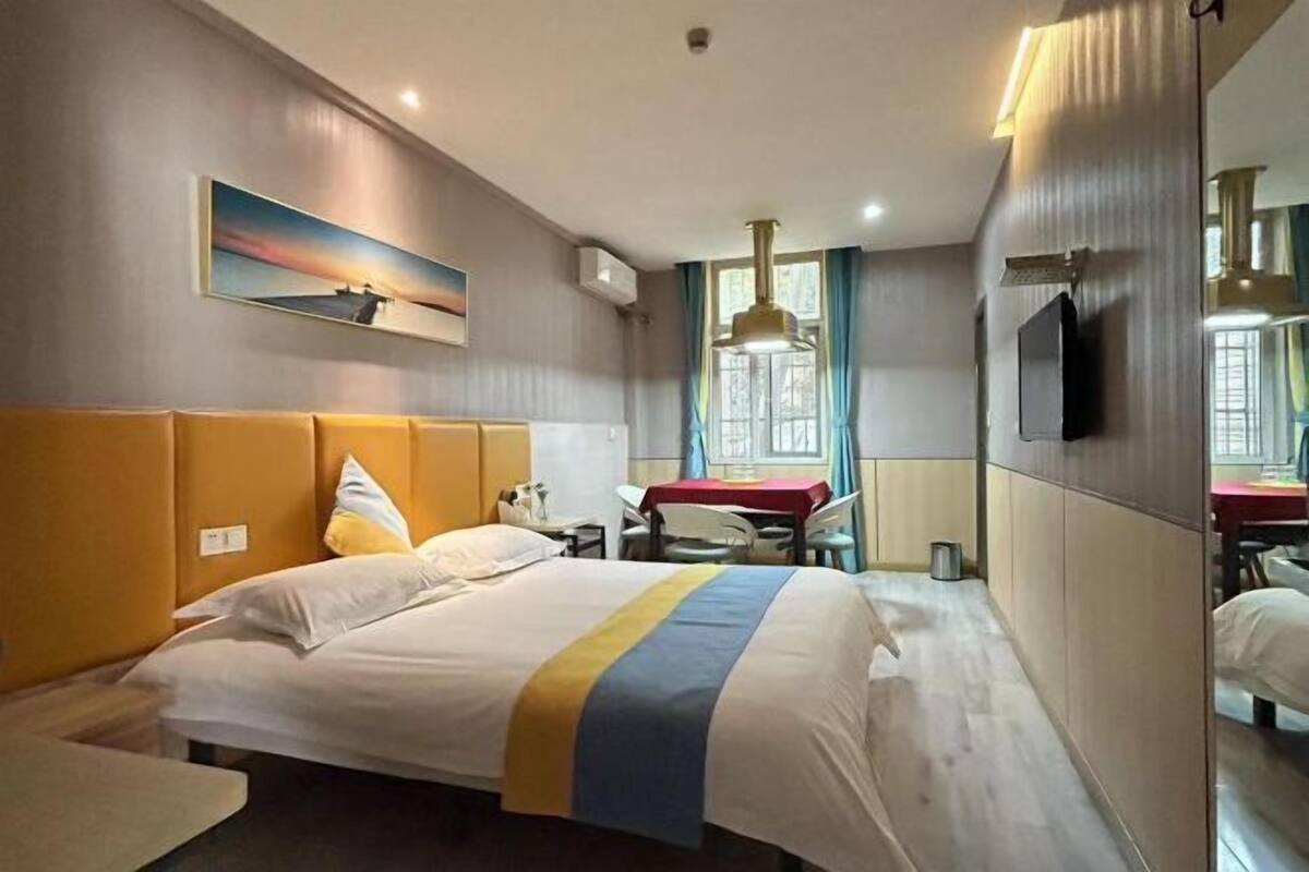 A hotel room with a bed, a desk, a chair, a TV, and a painting on the wall.