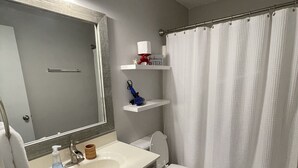 A bathroom with a white sink, mirror, and toilet. There are shelves above the toilet and a towel rack. - Quaint Beach 2-Bedroom Townhome - less than 2 blocks to the ocean! (Port St. Joe)
