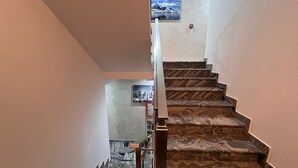 Una escalera con un diseño tipo mármol, barandilla y un cuadro colgado en la pared.