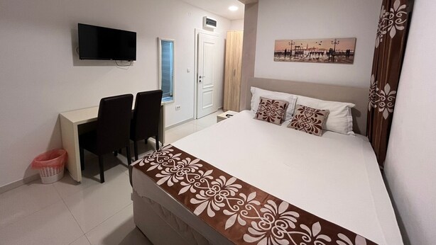 Una habitación de hotel con cama, escritorio, silla, televisor y puerta.