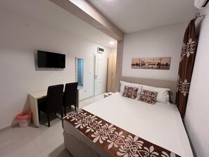 Une chambre d’hôtel comprenant un lit, un bureau avec une chaise, une télévision et une porte.