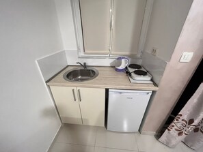A compact kitchenette with a sink, a small stove, and a dishwasher. - Pearl Apartments (Budva)